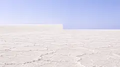 A white salt flat runs to the horizon under a pale sky, and halfway across, the horizon steps down a level like two photos badly joined. Someone will have to come out and fix that.