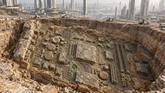 In an excavation pit beside a city of tall towers, the exposed rock is one huge fossilised circuit board, with ammonites set among the chips. Someone was here first.