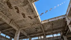 In a derelict concrete building, muddy footprints walk across the ceiling to a hole in the roof, then carry on as small white cloud prints across the blue sky. Whoever it was didn’t take the stairs.