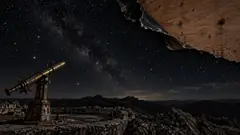 Over a ruined observatory in the mountains, a corner of the starry night sky peels back like old wallpaper to show bare plywood behind it. The telescope probably noticed first.